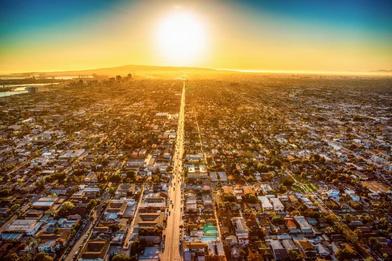 Aerial view of a grid-pattern city at sunset, with a straight main road stretching to the horizon.